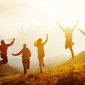 Group of five happy friends is running and jumping in sunset light on background of mountains. Happiness and friendship concept